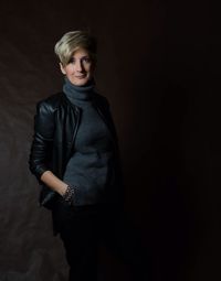 Portrait of young woman standing against black background