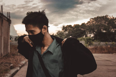 Portrait of young man looking at camera against sky