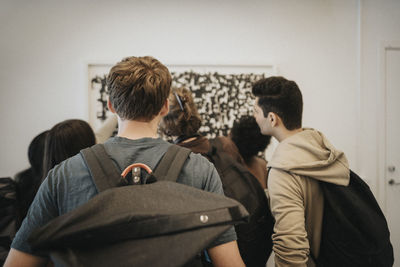 Rear view of students checking result on bulletin board in university