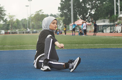 Athlete wearing hijab while sitting on sports track