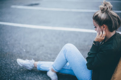 Man using mobile phone while sitting on road