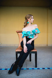 Full length of woman sitting against wall