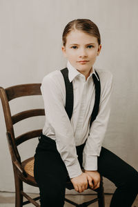 Girl sitting on chair against wall