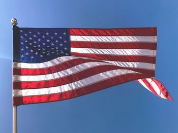 Low angle view of flag against blue sky