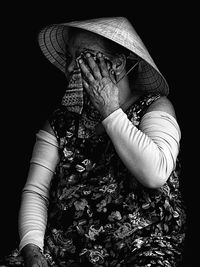 Close-up of woman wiping eyes with towel against black background