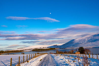 Scenic view of snow covered mountains against blue sky