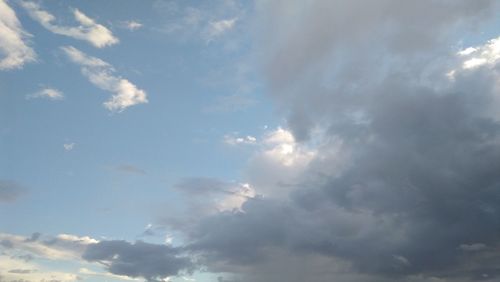 Low angle view of sunlight streaming through clouds