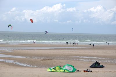 People kiteboarding on sea shore against sky