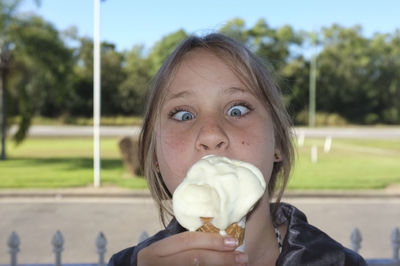 Girl making face while holding ice cream outdoors