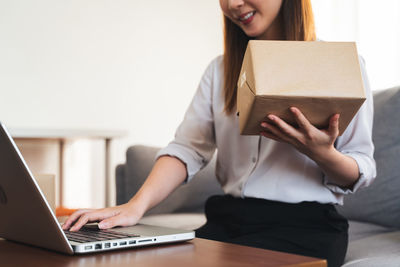 Midsection of woman using laptop on table