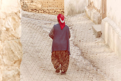 Rear view of woman wearing turkish flag headwear while walking on footpath