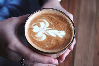 Close-up of hands holding coffee cup on table