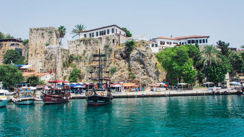 Boats in sea by buildings against clear sky
