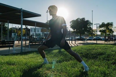 Boy stretching his legs in a park before running