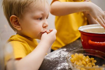 Children cook in the kitchen, boy eats raisins