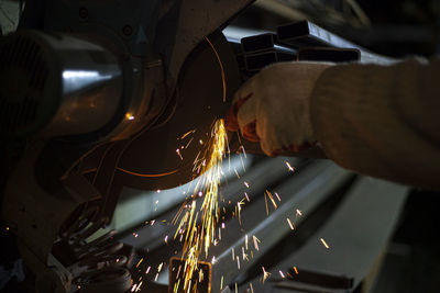 Midsection of person cutting metal with grinder