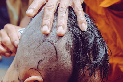Cropped hands of barber shaving customer head