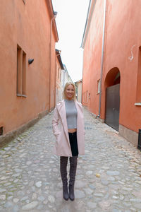 Full length woman standing on footpath amidst buildings