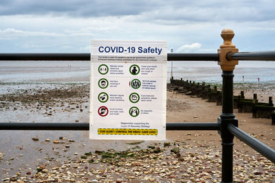 Information sign by railing against sky