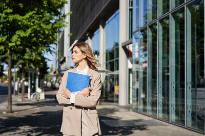 Portrait of young woman standing in city