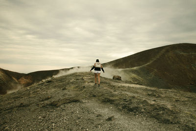 Rear view of woman walking on rocky landscape