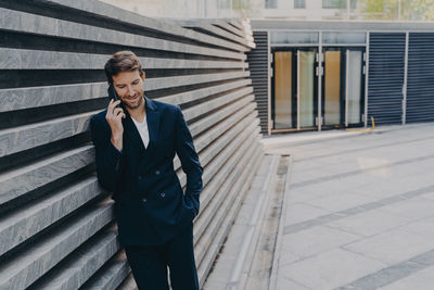 Full length of man using mobile phone while standing outdoors