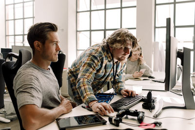 Male business coworkers working on computer in office
