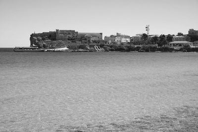 Sea by buildings against clear sky