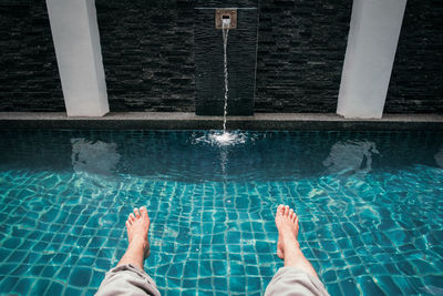 Low section of man relaxing in swimming pool