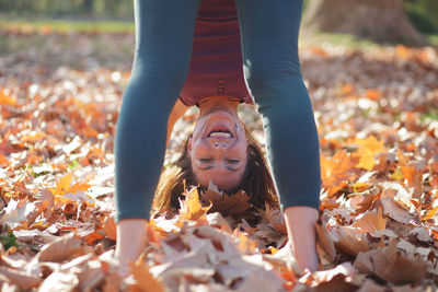 Portrait of woman bending while standing on autumn leaves