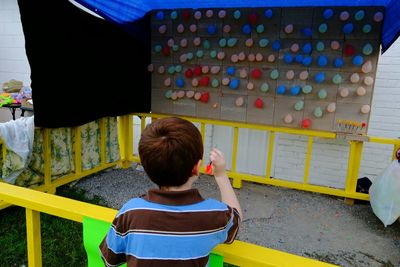 Rear view of boy aiming on balloons in yard