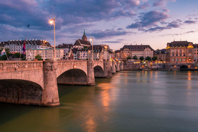 Arch bridge over river against buildings in city