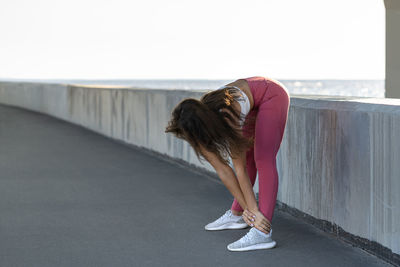 Full length of woman exercising while standing against bridge