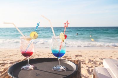 Close-up of wine glasses on beach against sky