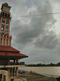 Bridge over river by buildings against sky