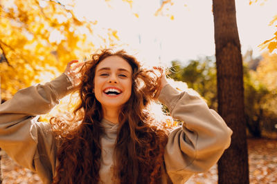 Portrait of young woman standing against trees