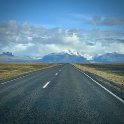 Road leading towards mountains against sky