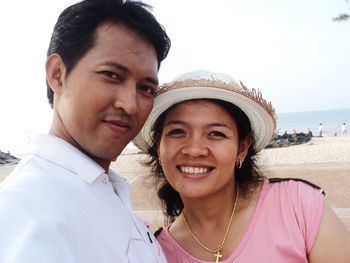 Portrait of smiling couple at beach against sky