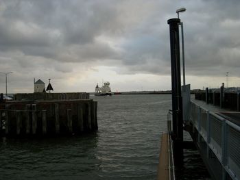 Pier on sea against cloudy sky