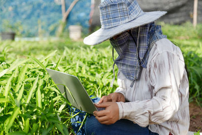 Side view of man using mobile phone in field