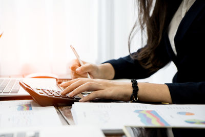 Midsection of woman using laptop on table