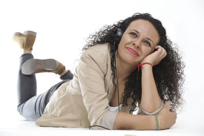 Portrait of beautiful young woman sitting against white wall