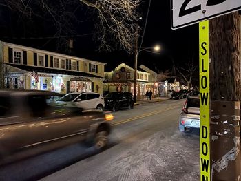 Illuminated road sign on street in city at night