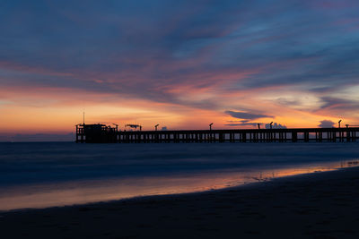 Silhouette pier on beach against sky during sunset