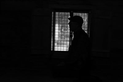 Side view of silhouette man standing by window at home