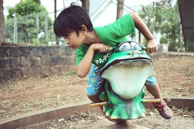 Full length of boy sitting on frog spring ride at playground