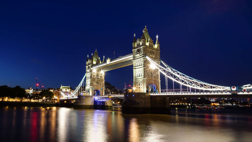 Illuminated bridge over river at night