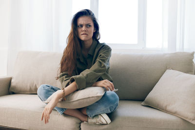 Young woman using laptop while sitting on sofa at home