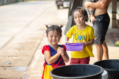 Portrait of a smiling girl holding camera while standing outdoors