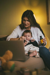 Mother feeding medicine to daughter in living room